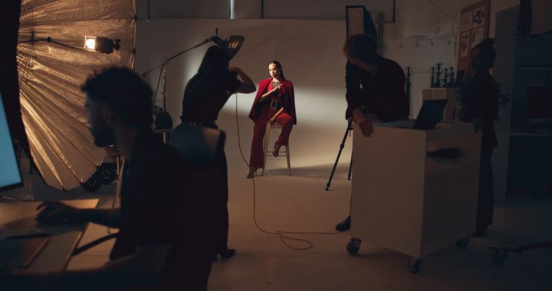 Photoshoot, photographer and group in studio, model and pictures for fashion magazine or production. Backstage, creative and people with project for media agency, camera and equipment for photography