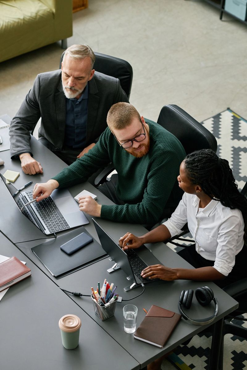 Group of business professionals discussing project strategy around conference table, with man pointing at laptop screen, engaging in productive discussion