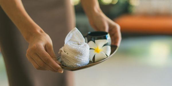 Person holding a tray with spa items and a flower.