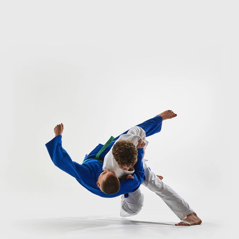 High-speed shoulder throw in progress, athlete in white executes flawless lift, blue gi fighter suspended mid-air, representing victory. Concept of championship, martial arts, combat sport, action.