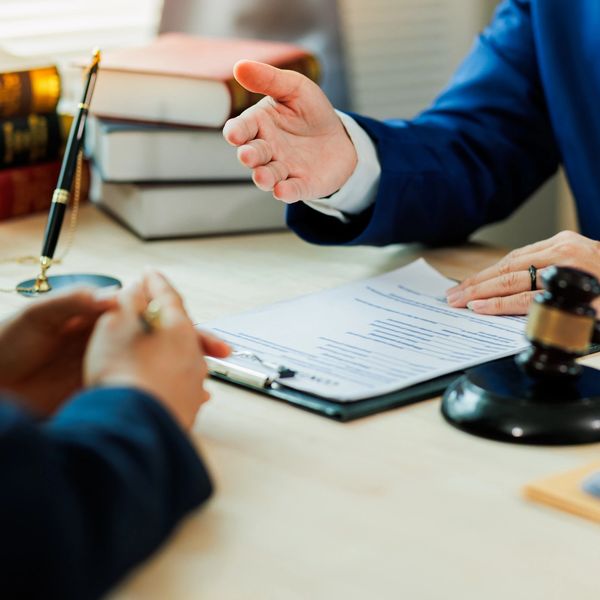 Two people in a legal consultation with documents and a gavel on the table.