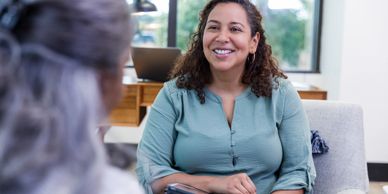A woman smiling warmly during a conversation in a cozy indoor setting.