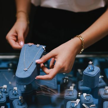 Person arranging jewelry display with rings and necklace