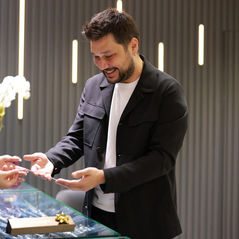 Elegant middle age businessman choosing and buying his new expensive watch. Beautiful youg female seller helps him to make good decision. Fashion style and elegance concept.