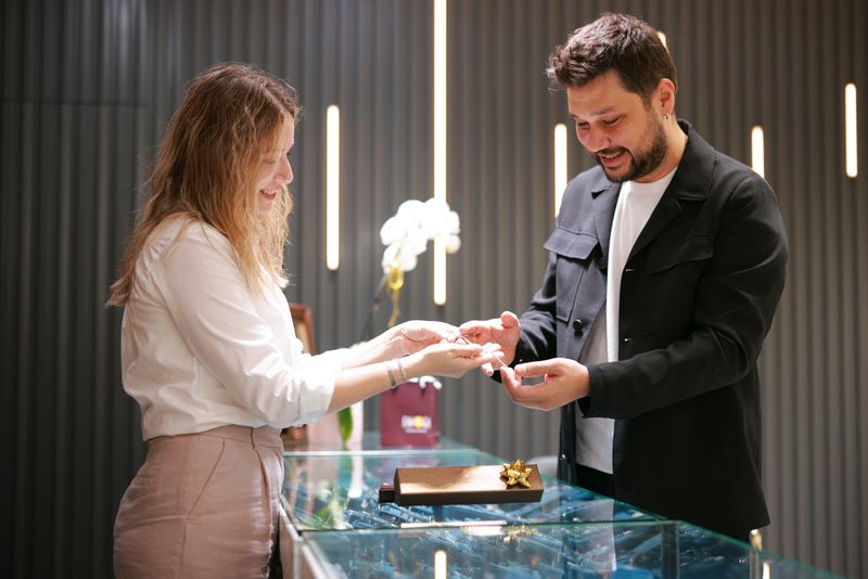 Elegant middle age businessman choosing and buying his new expensive watch. Beautiful youg female seller helps him to make good decision. Fashion style and elegance concept.