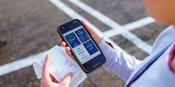 Person holding a phone displaying a digital payment app and a printed receipt.