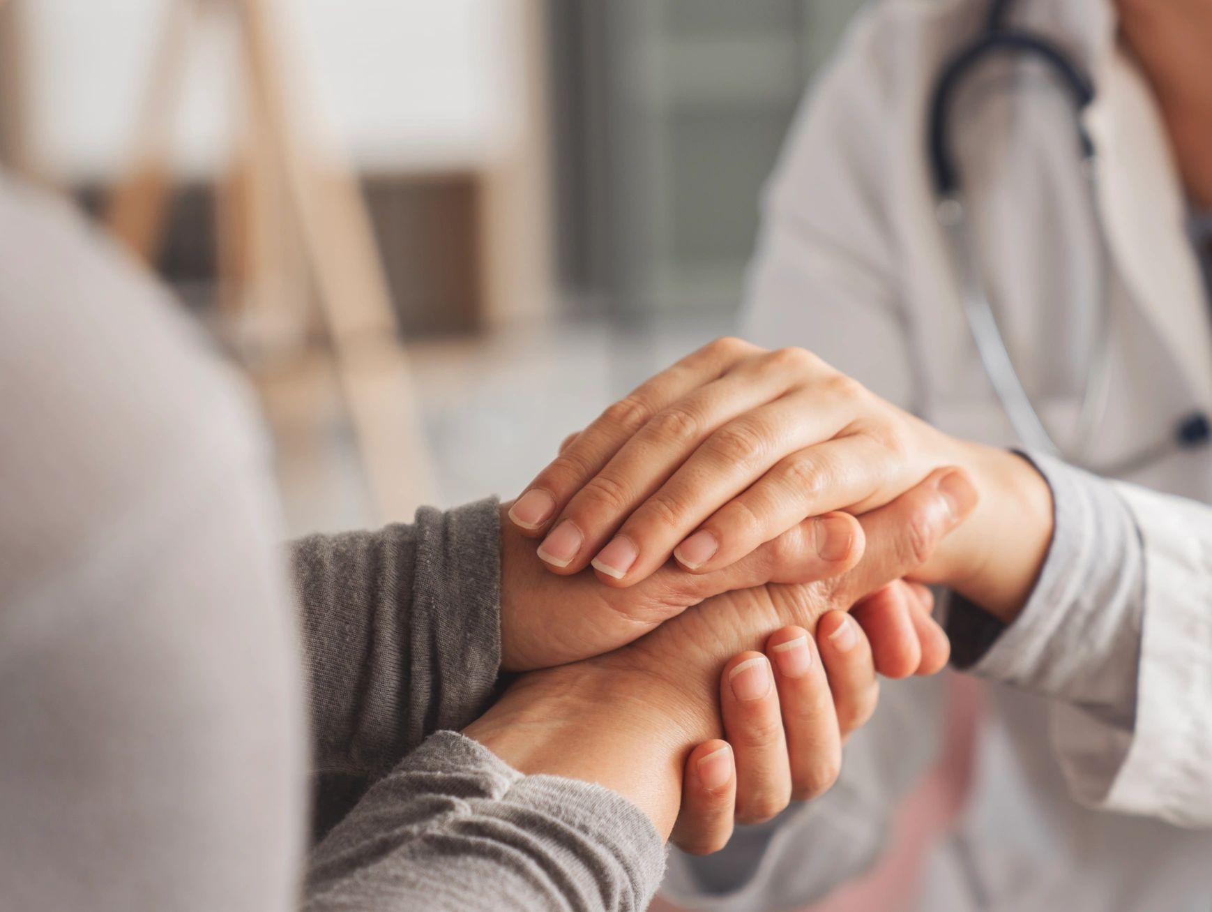 Doctor holding patient's hands in a reassuring manner.