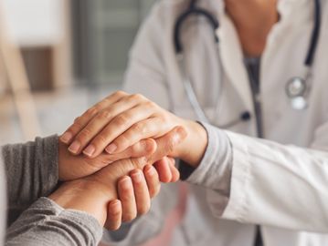 Doctor comforting patient by holding hands.