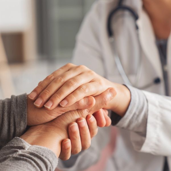 Doctor holding patient's hands in a comforting gesture.