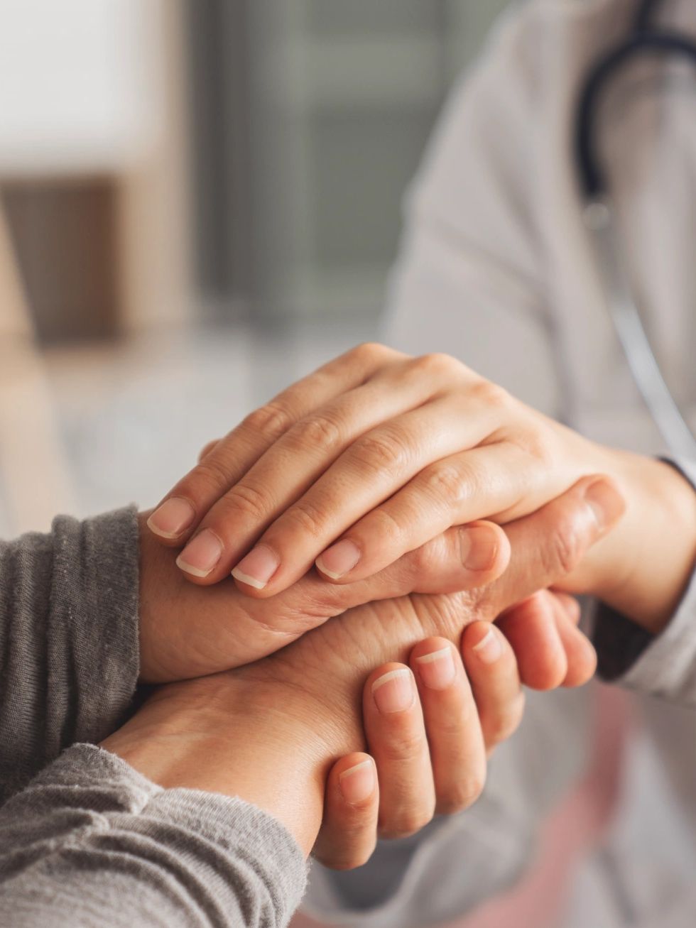 Doctor holding patient's hands in a reassuring manner.
