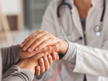 Doctor comforting patient by holding hands.