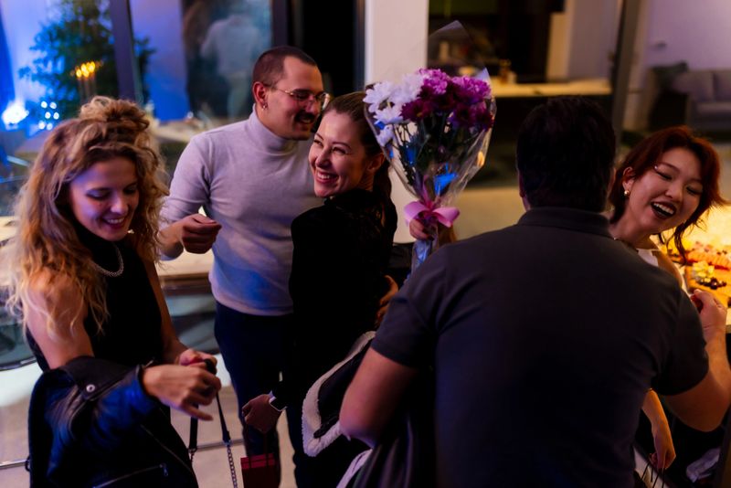 Close-knit friends share happy moments at an elegant indoor celebration, exchanging smiles, laughter, and gifts, creating a joyous atmosphere of friendship and warmth.