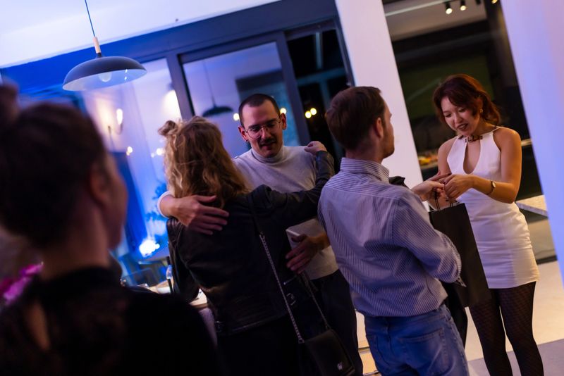 A social gathering in a contemporary setting where people engage in conversation and share moments. Attendees are casually dressed, showcasing relaxed atmosphere in a modern home environment.