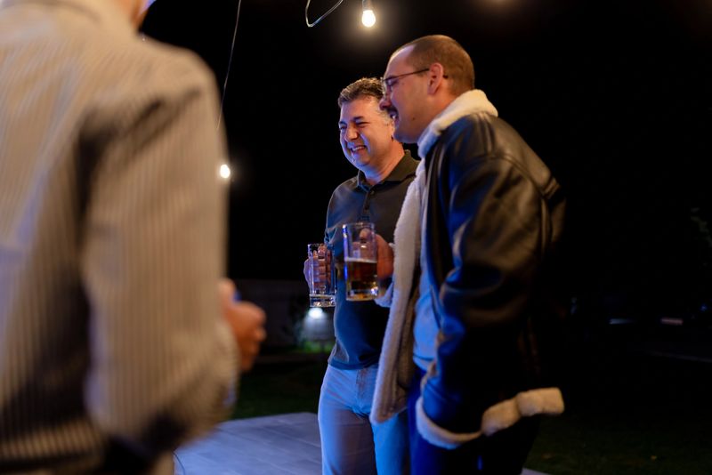 A captivating scene of friends enjoying drinks together outdoors in the evening, highlighting camaraderie, relaxation, and lively interaction in a casual environment under ambient lighting.
