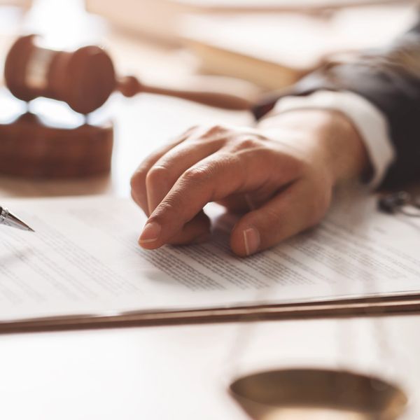 paralegal hand pointing at legal document with gavel in background.