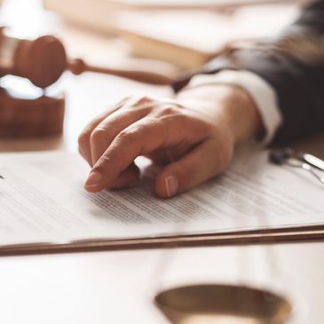 Hand pointing at document with a gavel nearby.