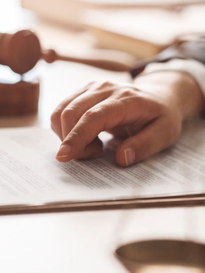 Hand pointing at document with judge's gavel nearby.