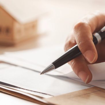 Close-up of a hand holding a pen over documents.