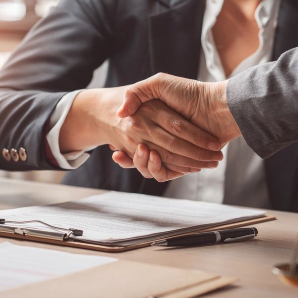 Two people shaking hands over a contract.