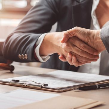 Two business professionals shaking hands over a signed contract.