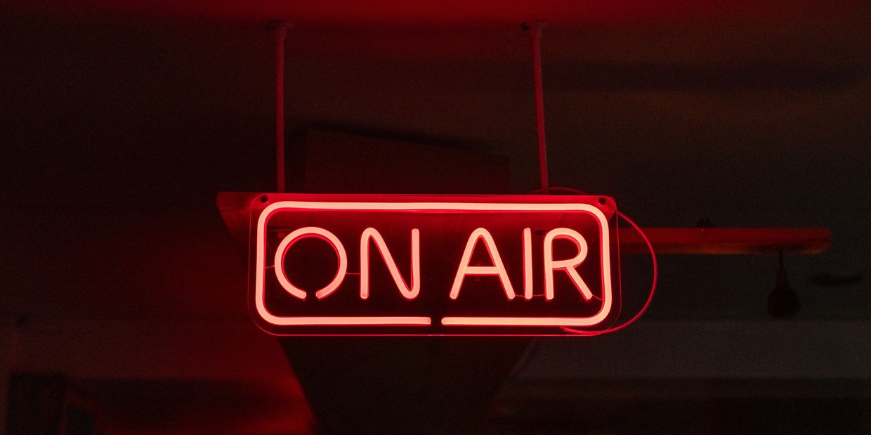 Red neon "ON AIR" sign glowing in the dark.
