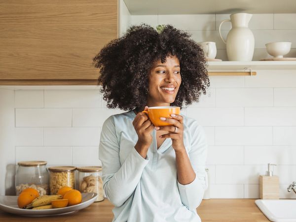 Woman in kitchen enjoying a cup of tea or coffee.