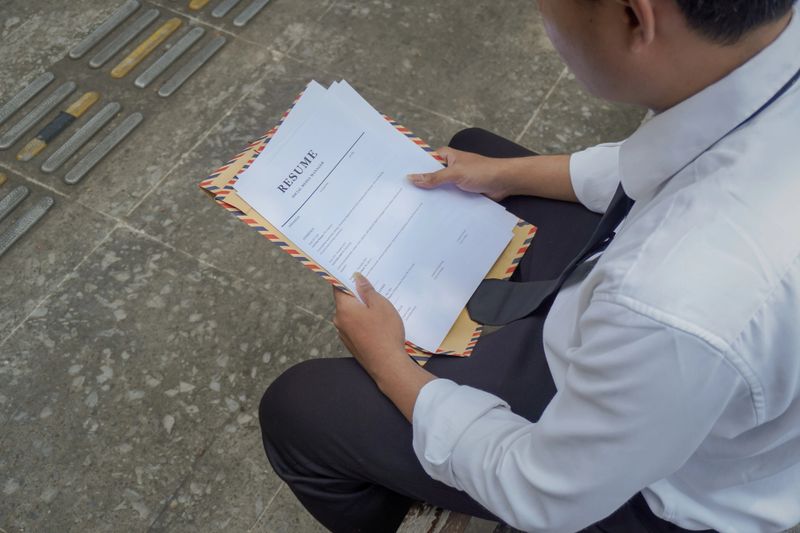 Close up of Asian job seeker holding his resume document for work application