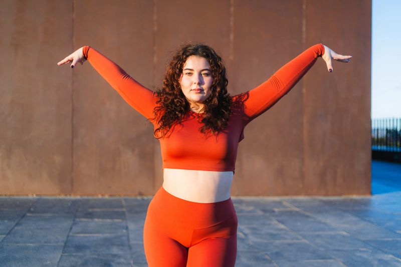 Confident curvy woman dancing with arms outstretched, celebrating body positivity and self-acceptance