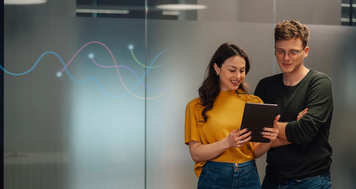 Two colleagues reviewing data on a tablet in a modern office.