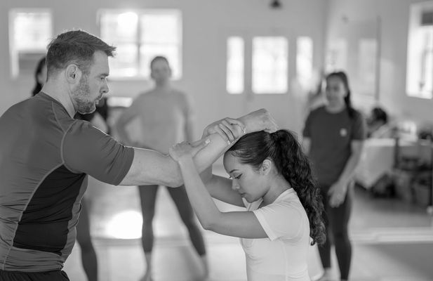 Martial artists practicing self-defense techniques in dojo.