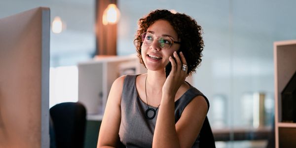 Young woman smiling while talking on phone at office desk.