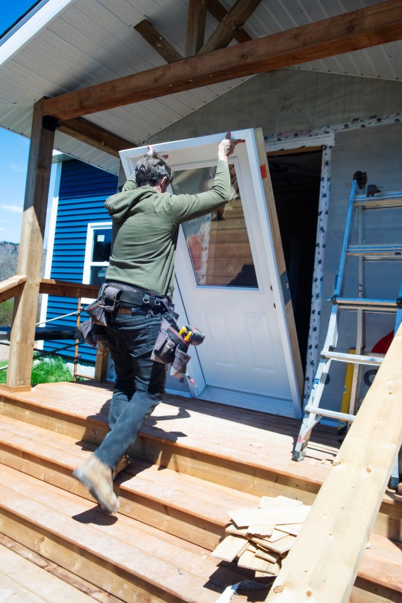 A mid-adult male contractor installing a new door during a renovation on an older home.
