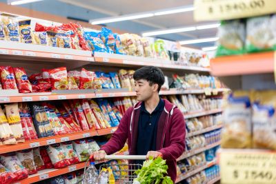 若い男性がスーパーマーケットで買い物をしている。