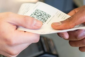 Two people exchanging a paper with a QR code.