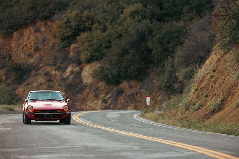 Couple traveling with a Vintage Car on Southern California mountain winding roads at sunset.
