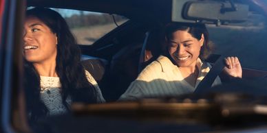 Two women smiling and enjoying a car ride together.