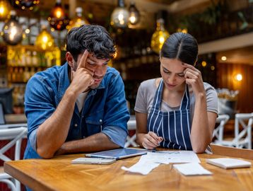 Two stressed workers reviewing documents in a restaurant.