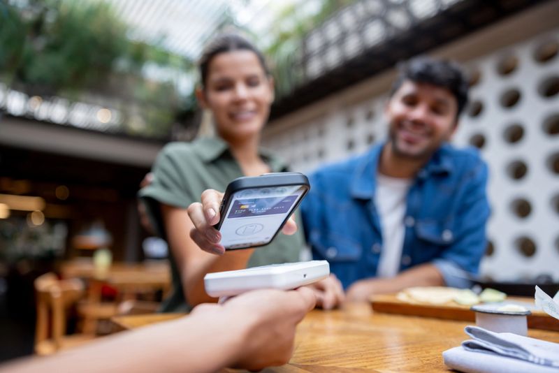 Close-up on a woman making a mobile payment at a restaurant - financial technology concepts