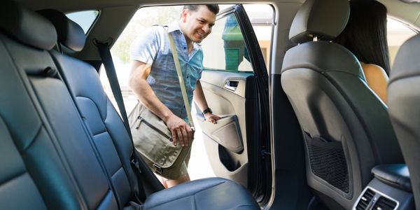 Man entering a car's backseat.
