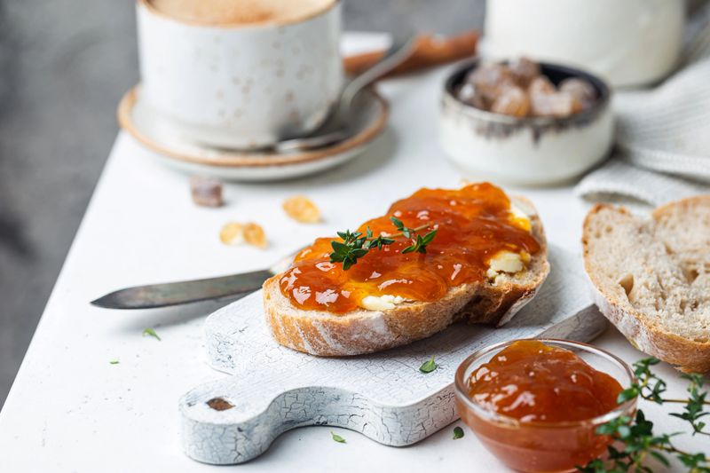 Closeup of pieces of white bread with apricot jam on light background