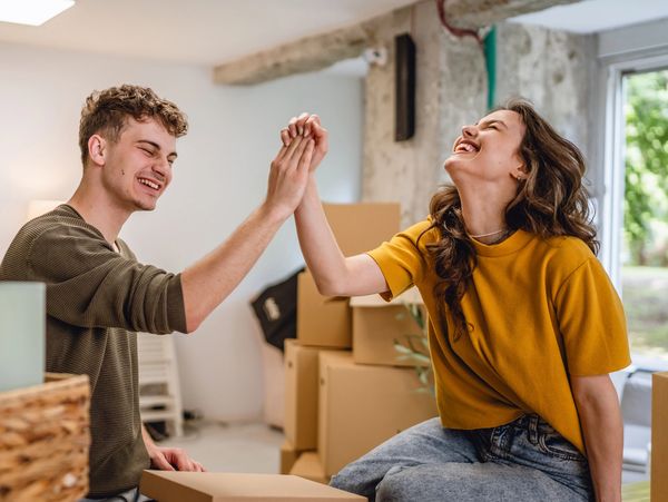 A young couple happily high-fiving while unpacking in their new home.