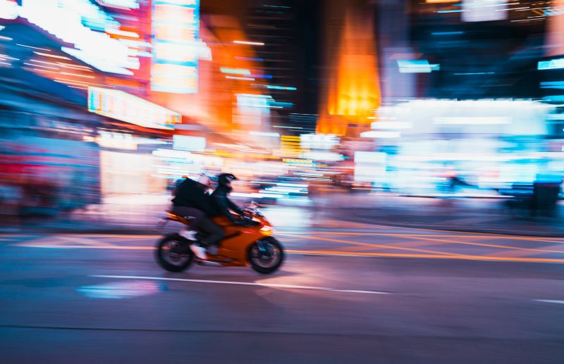 Motion blurred view of person on his motorcycle commuting through the Hong Kong city with high speed, blurred view of cityscape at night.