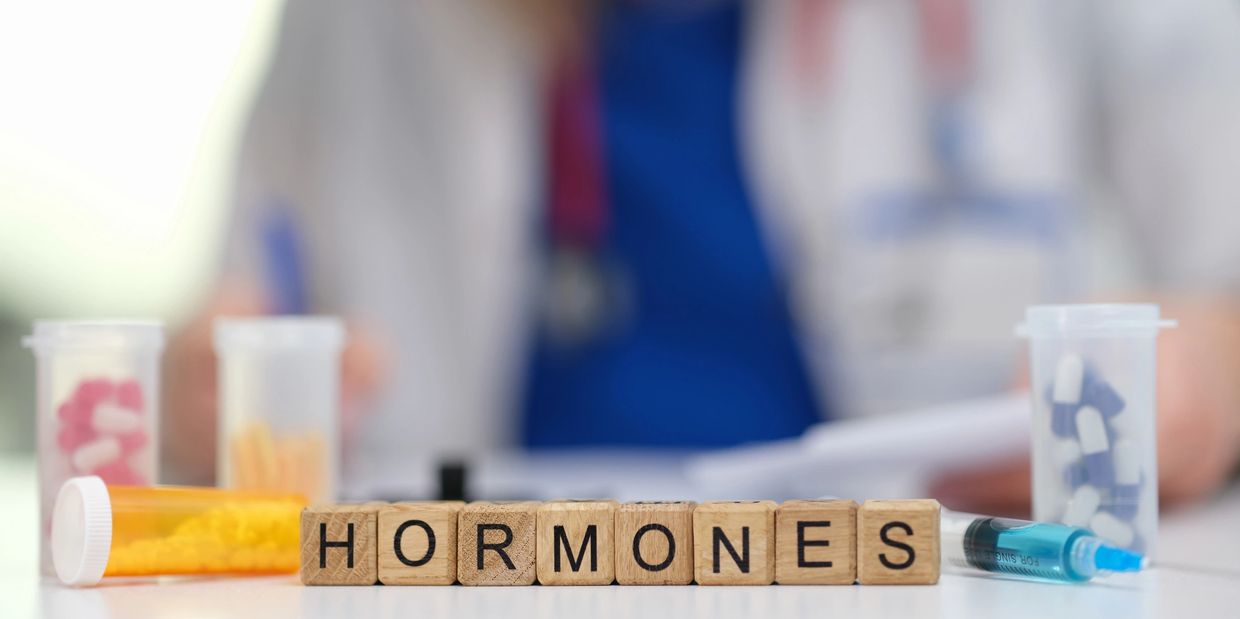 Wooden blocks spelling 'HORMONES' with pills and syringe.