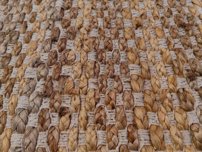 jute rug displays beautifully woven design with mix natural colors, creating warm and inviting atmosphere for any room. ideal for enhancing interior spaces. closeup.