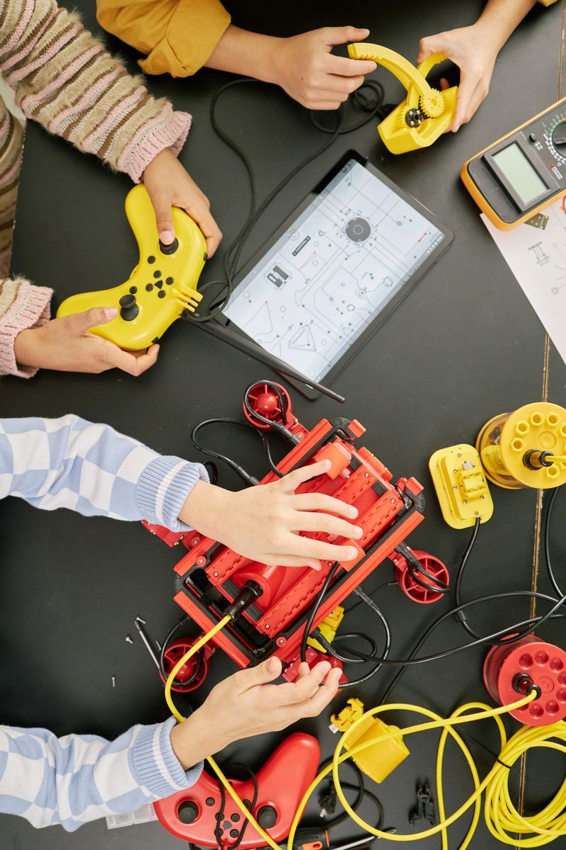 Group of students collaborating on an educational tech project, using various gadgets and tools for creating and innovating STEM projects in colorful, playful environment