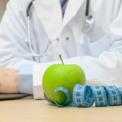 Green apple with measuring tape in front of a doctor.