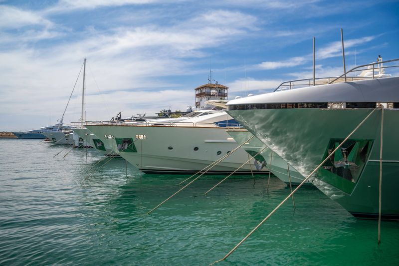 Polished superyachts line the harbor in Majorca, reflecting sunlight and luxury in a serene Mediterranean seascape.