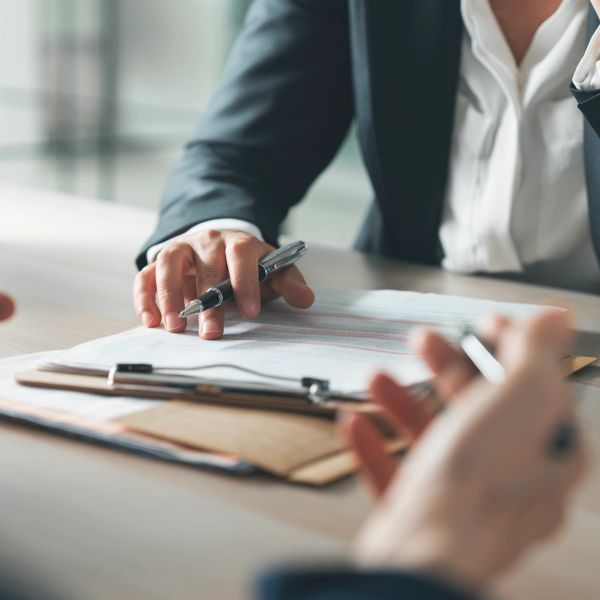 Two people discussing documents with pens in hand.