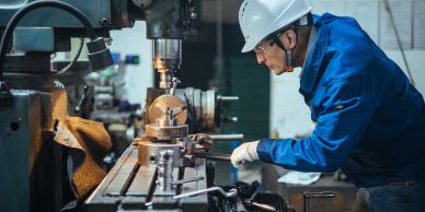 Worker operating a milling machine in workshop.
