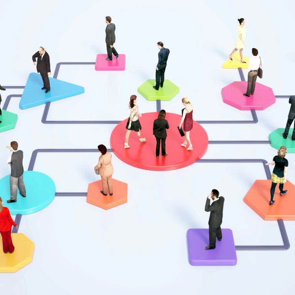 People standing on colorful connected shapes symbolizing a network or workflow.